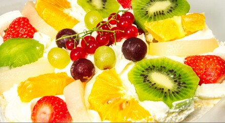 A colorful arrangement of sliced fruits including kiwifruit (Actinidia deliciosa), strawberries (Fragaria × ananassa), oranges (Citrus × sinensis), red and green grapes (Vitis vinifera), 