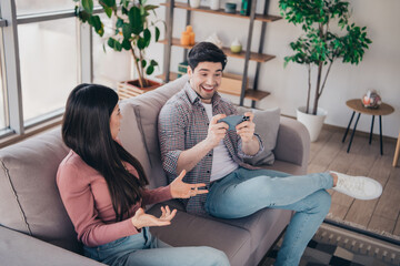 Obraz premium Young couple sitting on a sofa sharing moments and enjoying each other's company while relaxing in a cozy modern living room.