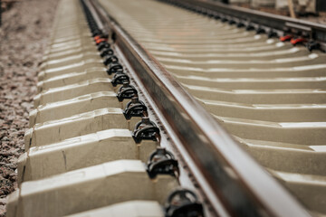 Detailed view of rusted steel railway tracks mounted on white concrete sleepers, captured at a...