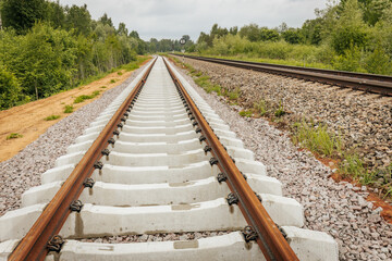 A curved section of newly laid railway track diverges beside an older line, with a circular signal...