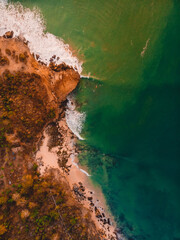 Top down view of rocky shore with ocean, waves and warm sun light