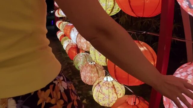 A Woman Hands Gently Touching Vietnamese Lanterns While Traveling
