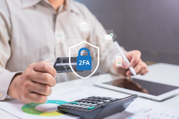 Person using two-factor authentication with credit card, calculator, and tablet for secure online...