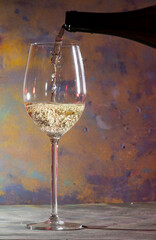 glass and bottle of white wine with corkscrew and blurred abstract background
