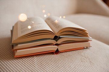 Stack of open paper books with glowing magic lights close up