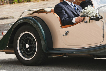 Groom in a vintage convertible retro car at a wedding.