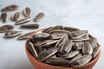Black sunflower seeds in a bowl  on light background,closeup
