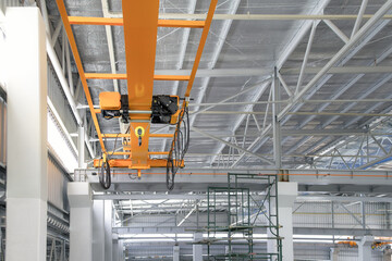 Overhead crane inside factory or warehouse building. Industrial machine or lifting equipment consist of hoist, hook and wire rope move on beam girder structure for manufacturing production plant.