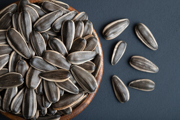 Black sunflower seeds in a bowl on concrete background
