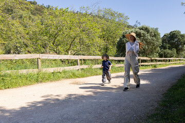 Obraz premium Mother and son walking on a country road in summer