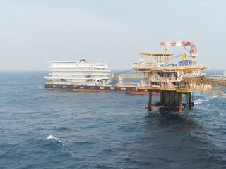 Offshore oil platform and support vessel navigate rough seas. A glimpse into the energy industrys complex operations at sea, showcasing the scale and challenges of offshore energy production.