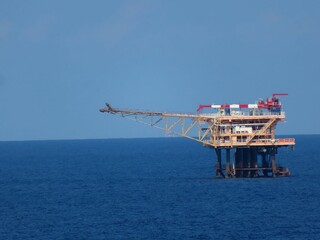 Offshore Oil Platform on a Calm Ocean Under a Clear Blue Sky. A solitary structure against the vastness of the sea, symbolizing industry and exploration.