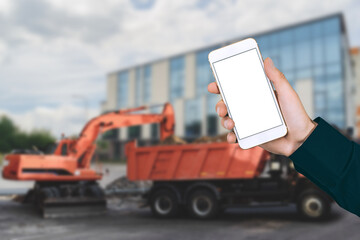 Mockup of a smartphone in a man's hand against the background of a construction site.
