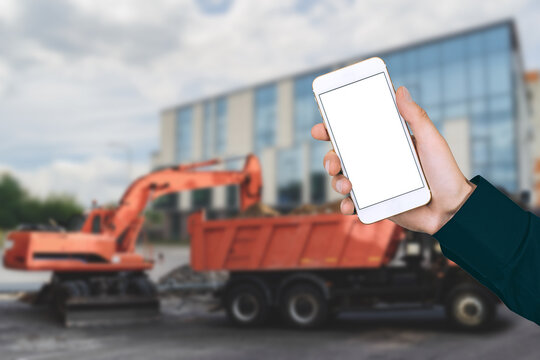 Mockup of a smartphone in a man's hand against the background of a construction site. - Powered by Adobe