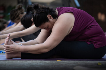 Woman doing seated forward bend yoga pose outdoors