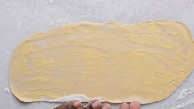 Overhead view of rolled paratha dough on a marble countertop, top view of flaky flatbread dough, process of making paratha