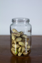 Glass Jar Filled with Pistachio Nuts on Wooden Surface