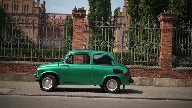 A charming green classic car is parked beside a striking historic building, showcasing its vintage design against a backdrop of elegant architecture and greenery. hunchbacked Cossack, zaz 965