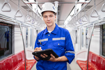 Portrait of young engineer of electric locomotive holding tablet in train