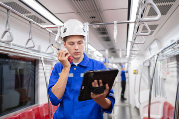 Portrait of young engineer of electric locomotive holding tablet in train