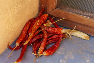 Pile of dried red chili peppers in a rustic corner with natural light. Spicy and textured, perfect for culinary or organic food themes