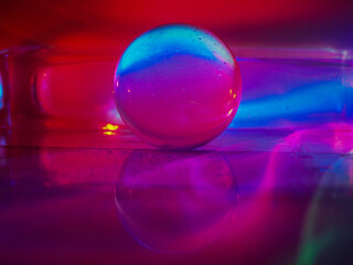 A clear glass ball is sitting on a pedestal. Colorful background. Abstract graphic background. Light effect. Planet in a space mood and feel.