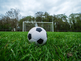 Fototapeta premium Classic style soccer or football on neatly cut green grass with small training goal posts in the background. Play area in a park. Sport and entertainment concept.