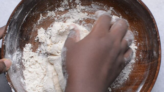 Overhead view of paratha dough being mixed in a wooden bowl, top view of flaky flatbread dough in a wood bowl, process of making paratha