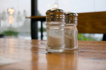 Salt and pepper shakers on wooden table in cafe
