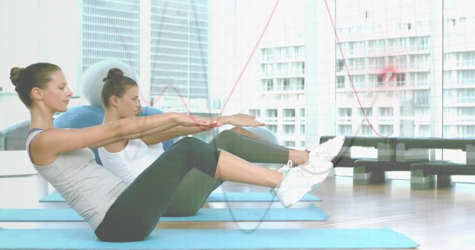 Group responding to cue performing V-sit pulses for core fitness on blue mats under clear overlay