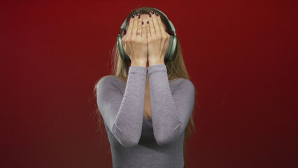 Woman with headphones expressing joy and disappointment against a vibrant red background,...
