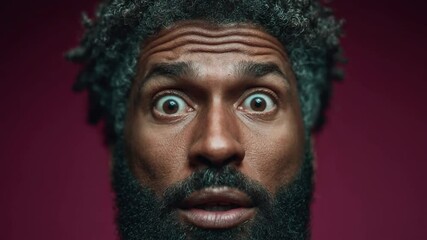 Man with wide eyes from shock or terror presses hands to his face against a dark background, conveying intense surprise, fear, or mental health concepts and unexpected events impact
