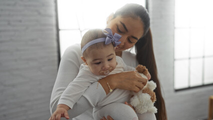 Woman holding baby in cozy living room, showcasing family love and tenderness in a bright indoor...
