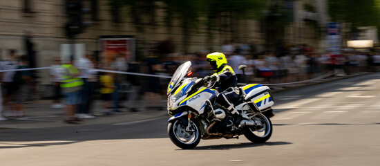 Fototapeta premium Emergency Response Motorcycle Police Officer Patrolling City Streets With Dynamic Motion Blur Effect During High-Speed Urban Law Enforcement Operation