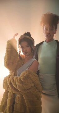 Vertical video: Posing confidently, women in stylish outfits under dramatic studio lighting in studi