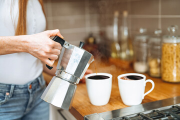Brewing fresh coffee in a cozy kitchen while pouring steaming beverage into white cups