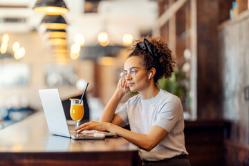 Interracial female freelancer sitting in cafe and working on a laptop.