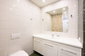 Bright bathroom with white tiles, a vanity with a sink, and a large mirror reflecting colorful mosaic tiles. Minimalist design with clean lines
