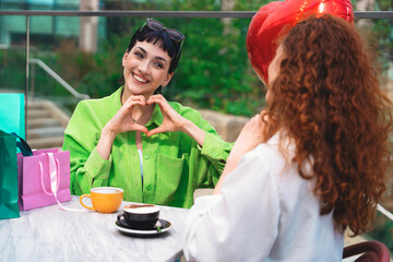 Friends enjoy a cheerful afternoon at a cafe while sharing a heartfelt moment with coffee and gifts in a vibrant urban setting