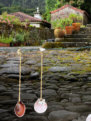 scallops hanging on chords at the entrance to the garden with cobblestones in portugal on the...