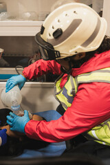 Latina paramedics, providing first aid inside the ambulance to a patient, using the air pump and...