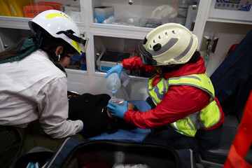 Latina paramedics, providing first aid inside the ambulance to a patient, using the air pump and measuring oxygen.
