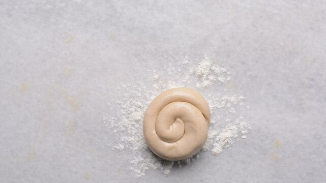 Overhead view of rolled paratha dough on a marble countertop, top view of flaky flatbread dough, process of making paratha