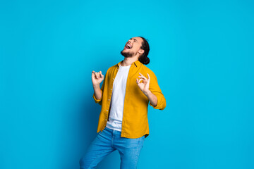 Energetic young man in a yellow shirt expressing excitement against a vibrant blue background