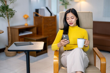 A woman is sitting in a chair with a cell phone in her hand