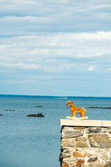 A toy tiger on a ledge with the ocean in the background 