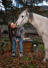 Young woman standing next to her Arabian horse, giving it a kiss