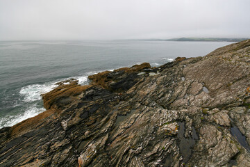 Rocky shore near Falmouth, calm sea and overcast sky in distance