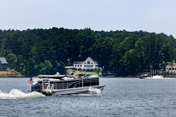 Boaters on pontoon boat enjoying summer day on Lake. Pontoon party boat cruising on freshwater lake.