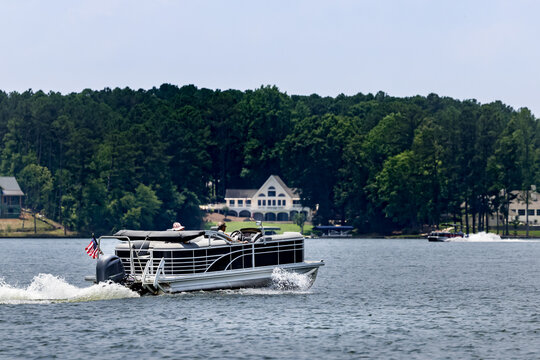 Fototapeta Boaters on pontoon boat enjoying summer day on Lake. Pontoon party boat cruising on freshwater lake.